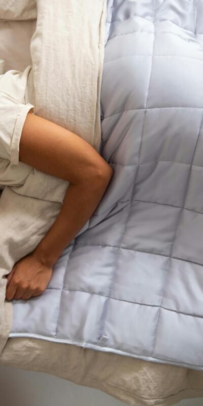 Young woman peacefully resting with a weighted blanket, enjoying relaxation and comfort.